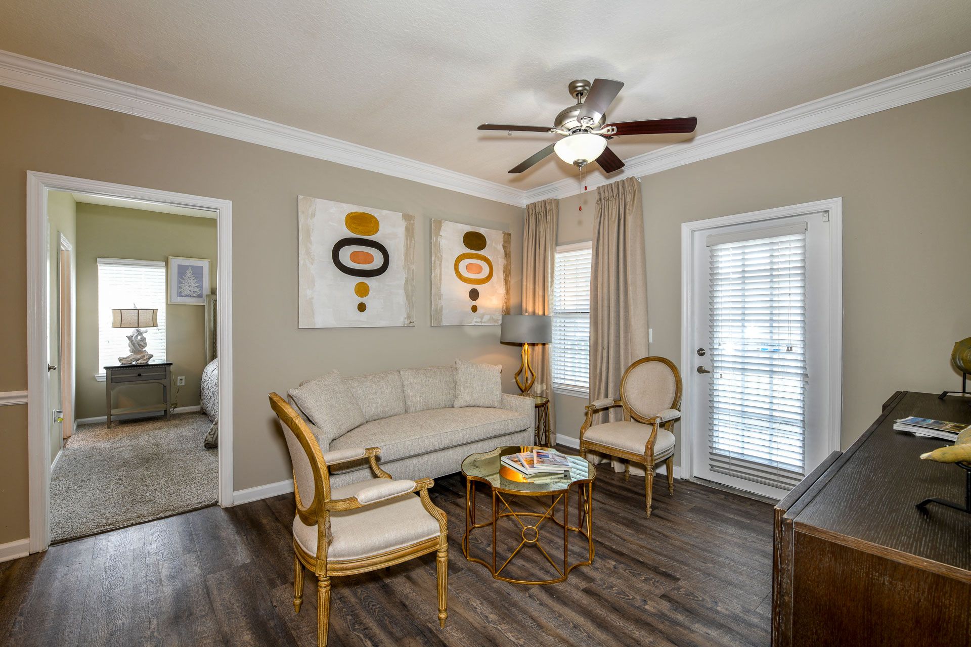 a living room with a couch and chairs and a ceiling fan